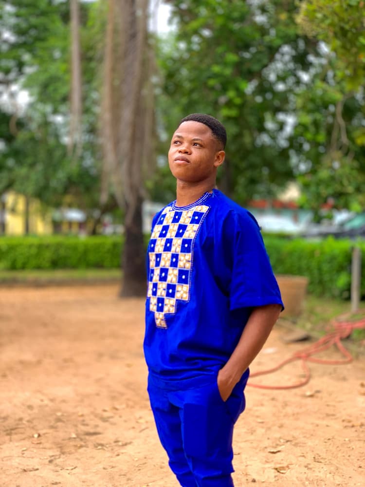 Portrait of Arès Gnimagnon in blue traditional attire, outdoors
